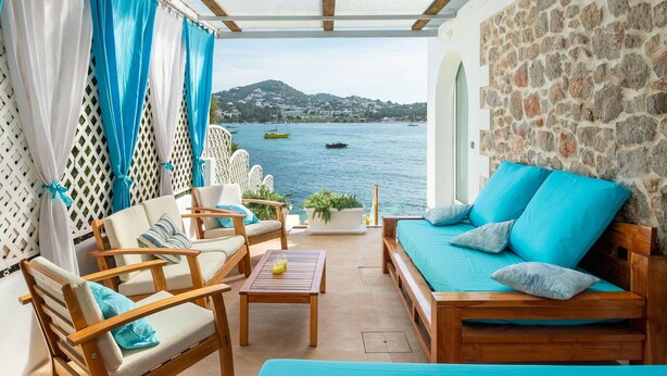 Un espacio al aire libre acogedor con mobiliario de madera y vistas al mar.