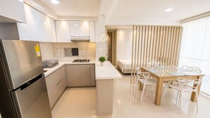Eine moderne Küche mit integriertem Kühlschrank, Herd und Spüle. Es gibt einen Essbereich mit einem Holztisch und Stühlen.
