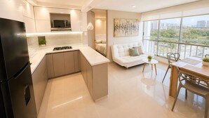 Eine moderne Küche mit integriertem Mikrowellenherd, Gasherd und Kühlschrank. Es gibt einen Essbereich mit Tisch und Stühlen sowie ein Sofa im Wohnzimmer.