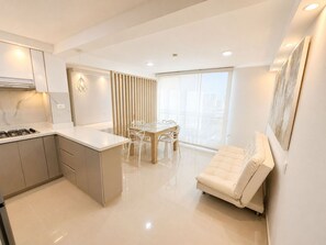 A modern kitchen with a dining area, a sofa, and a large window. - Apartamentos Palmar - by SOHO (Puerto Colombia)