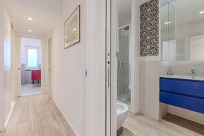 Un baño moderno con cabina de ducha de vidrio, un lavamanos blanco y armarios azules.