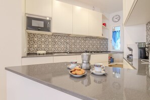 A modern kitchen with a microwave, coffee maker, and a breakfast setup on the counter. - Journalist Apartment Sistine Chapel (Roma)