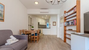 Een moderne woonkamer met een bank, een eettafel, stoelen, een boekenkast en een televisie.
