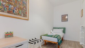 Een slaapkamer met een bed, een bureau, een stoel en een radiator.