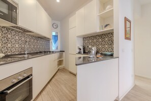 Una cocina moderna con armarios blancos, horno empotrado, microondas y un salpicadero con diseño.