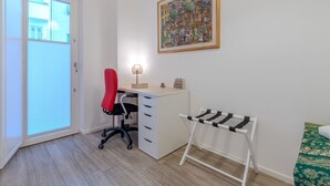 Een kamer met een bureau, stoel en een droogrek.