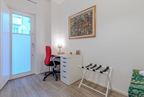 A room with a desk, chair, and a drying rack.