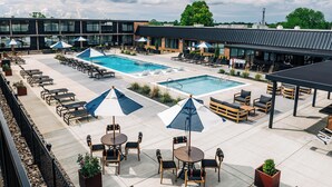 A rooftop pool area with lounge chairs, umbrellas, and a bar area. - The Trail Hotel (Bardstown)