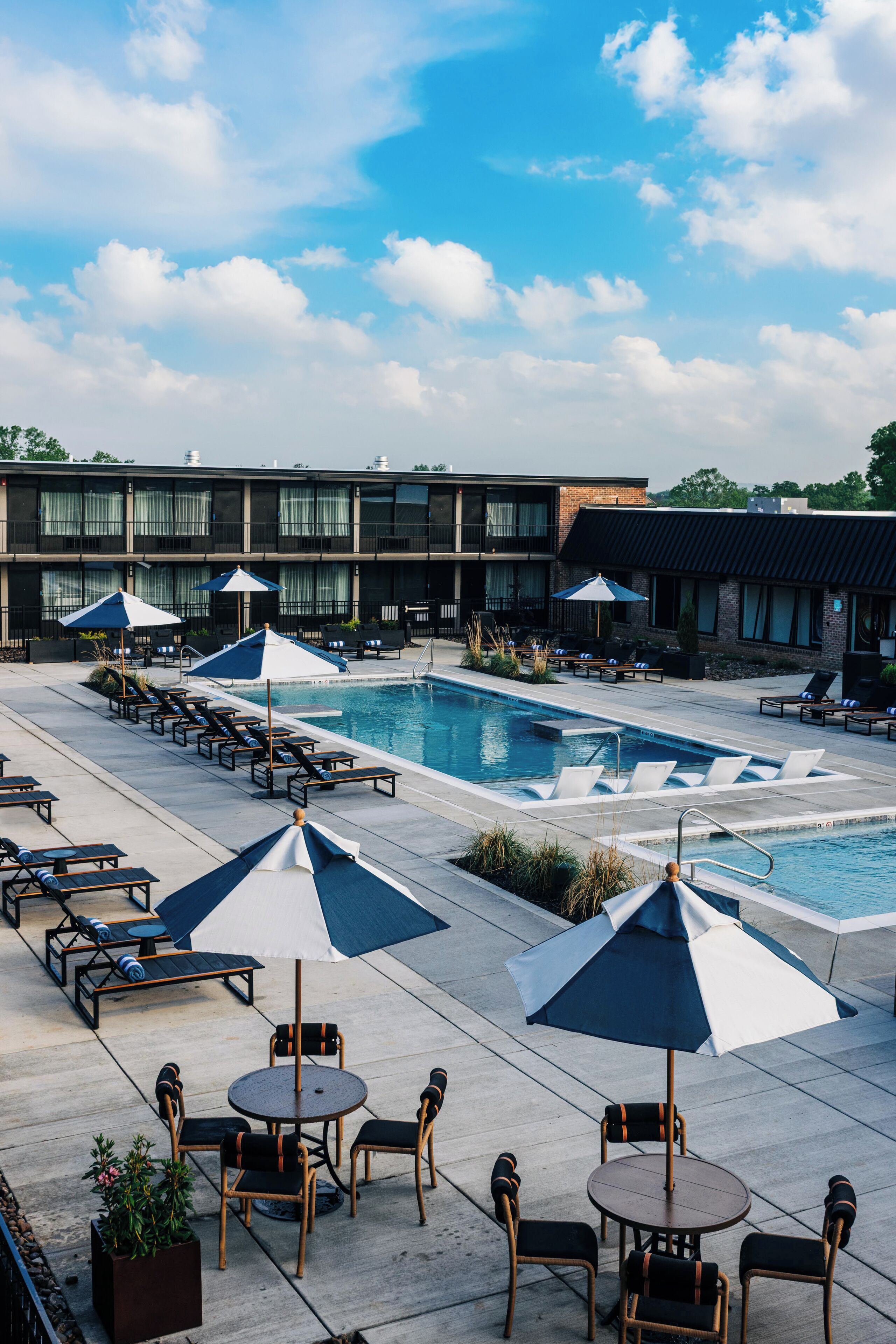 A poolside area with lounge chairs, umbrellas, and a pool.