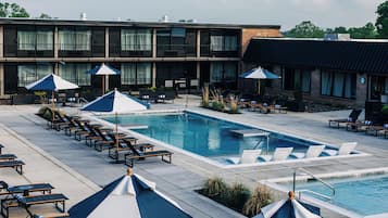 A poolside area with lounge chairs, umbrellas, and a pool.