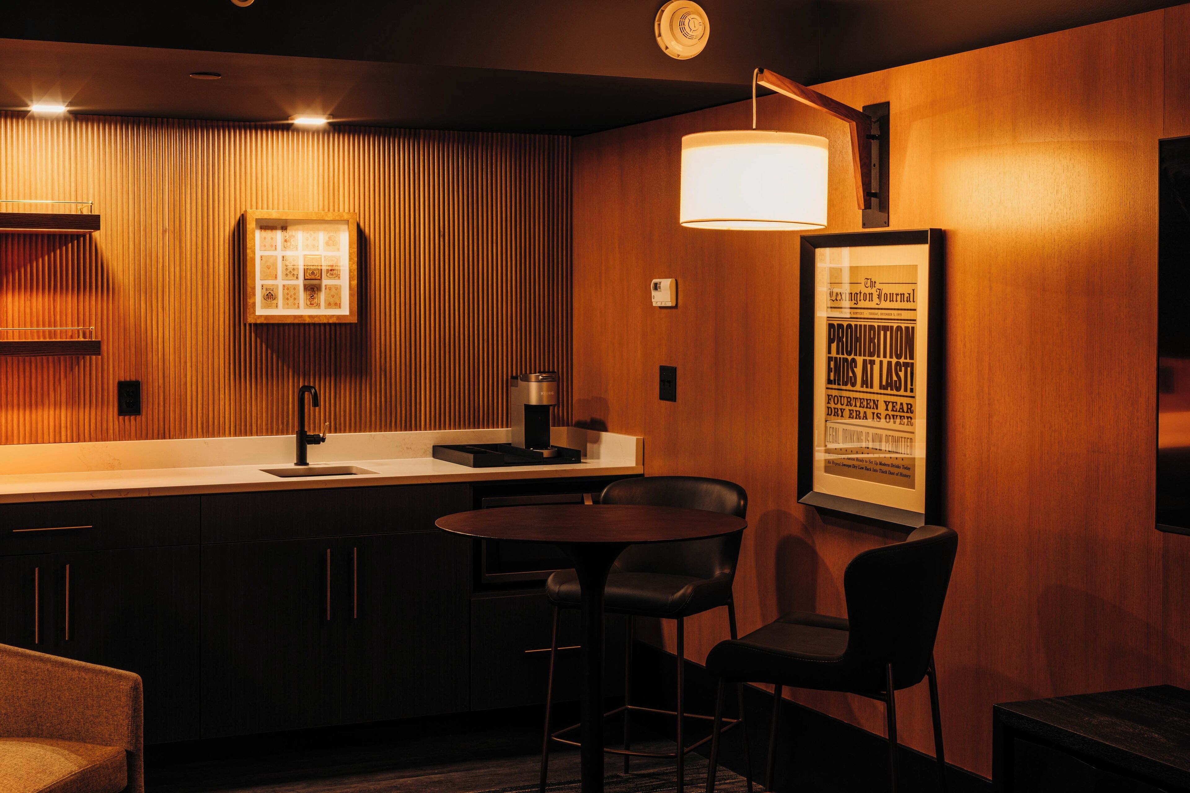 A modern kitchen with a wooden finish, a bar area with stools, and a framed newspaper on the wall.