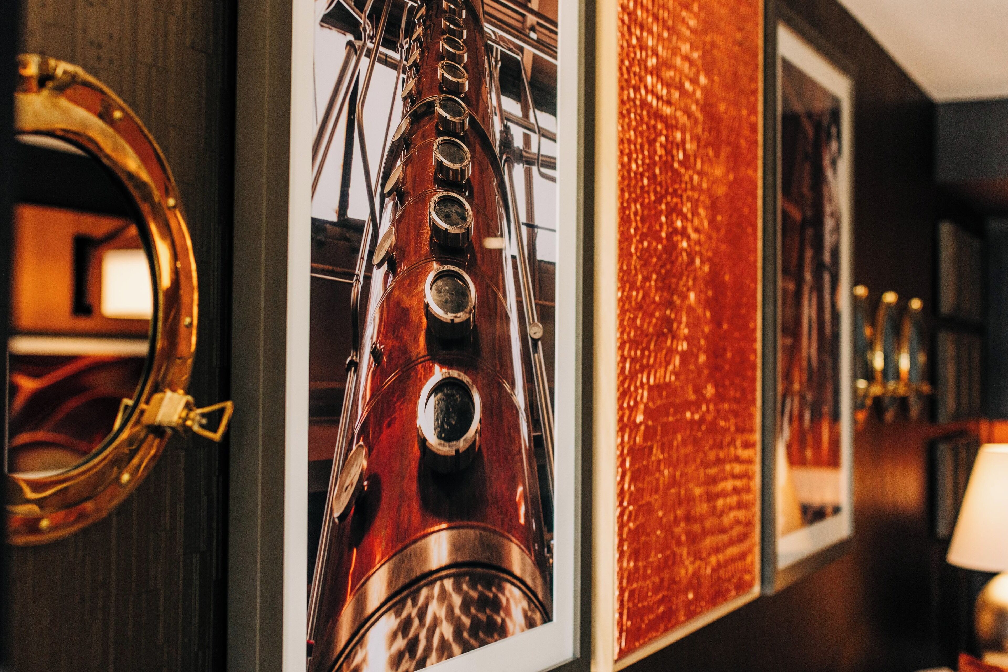 A wall with framed pictures, including a brass telescope and a wooden ship.