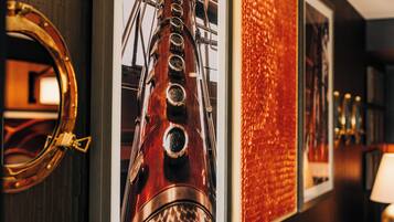 A wall with framed pictures, including a brass telescope and a wooden ship.