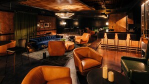A modern lounge area with leather seating, a bar, and ambient lighting. - The Trail Hotel (Bardstown)