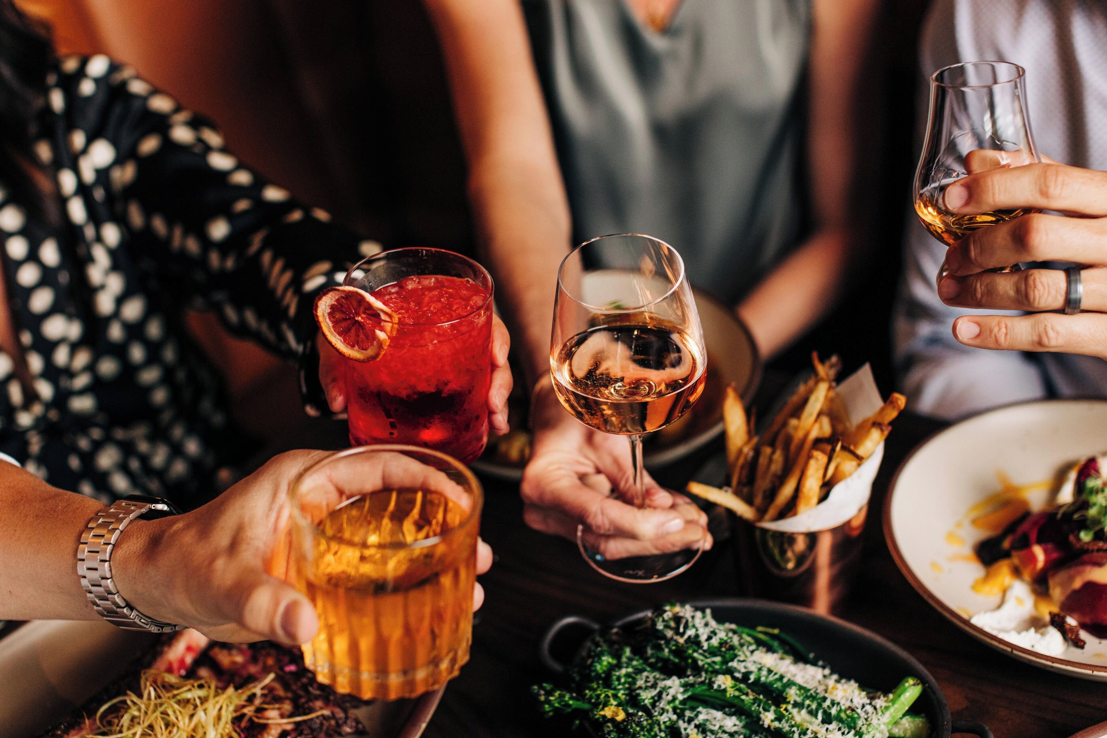 Un grupo de personas sosteniendo bebidas y platos de comida, lo que sugiere una reunión social o una comida.