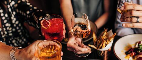 Un grupo de personas sosteniendo bebidas y platos de comida, lo que sugiere una reunión social o una comida.