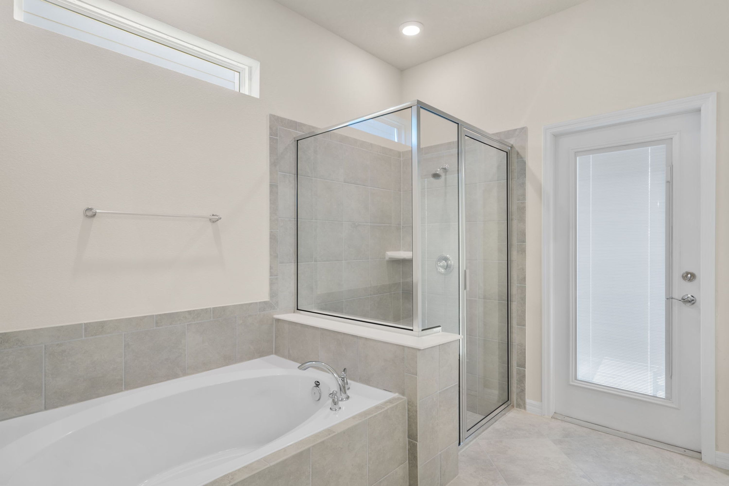 A modern bathroom with a glass-enclosed shower, a standalone bathtub, and a frosted door.