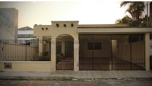 A residential building with a gated entrance, a covered porch, and a visible garage door. - Suite - Casa Granada 347. Executive BnB (Mérida)