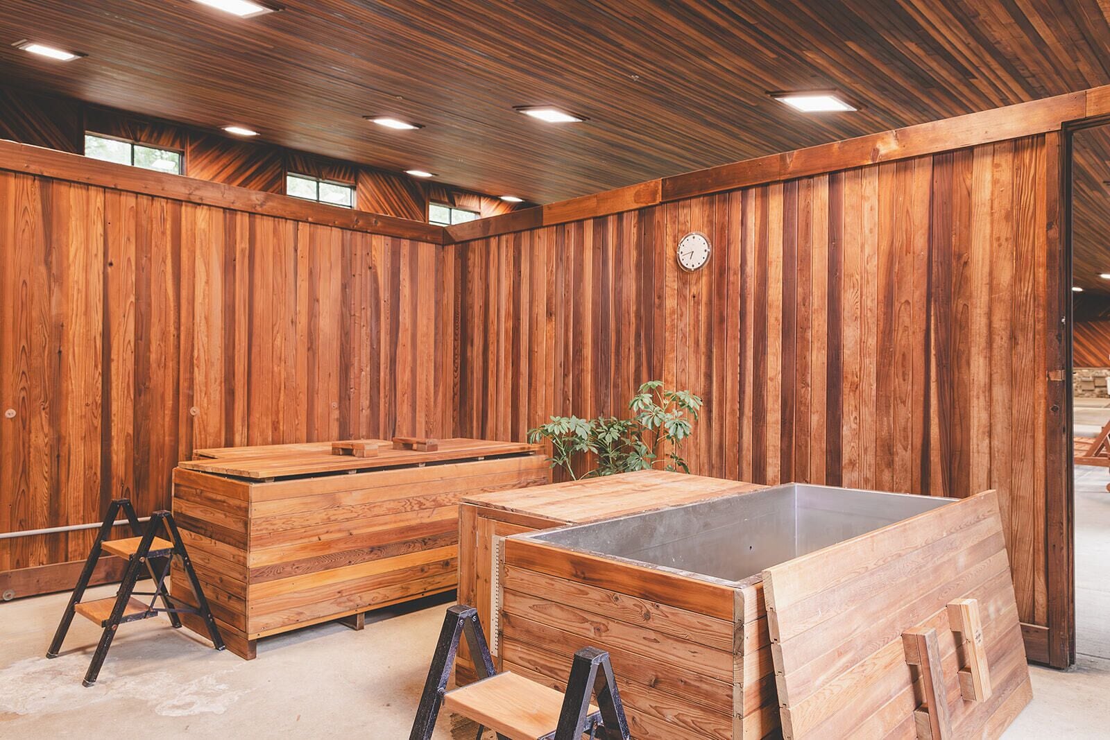 Interior de madera con sauna, bancos de madera y un reloj en la pared.