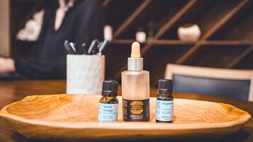 A wooden tray with three bottles of essential oils and a dropper on a table.