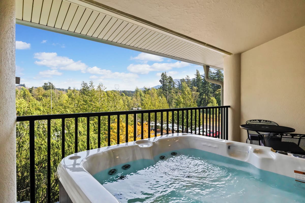 Un bain à remous sur un balcon avec vue sur les arbres et les montagnes.