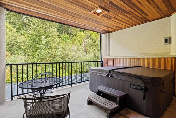 Un espacio al aire libre cubierto con un jacuzzi, una mesa y sillas.