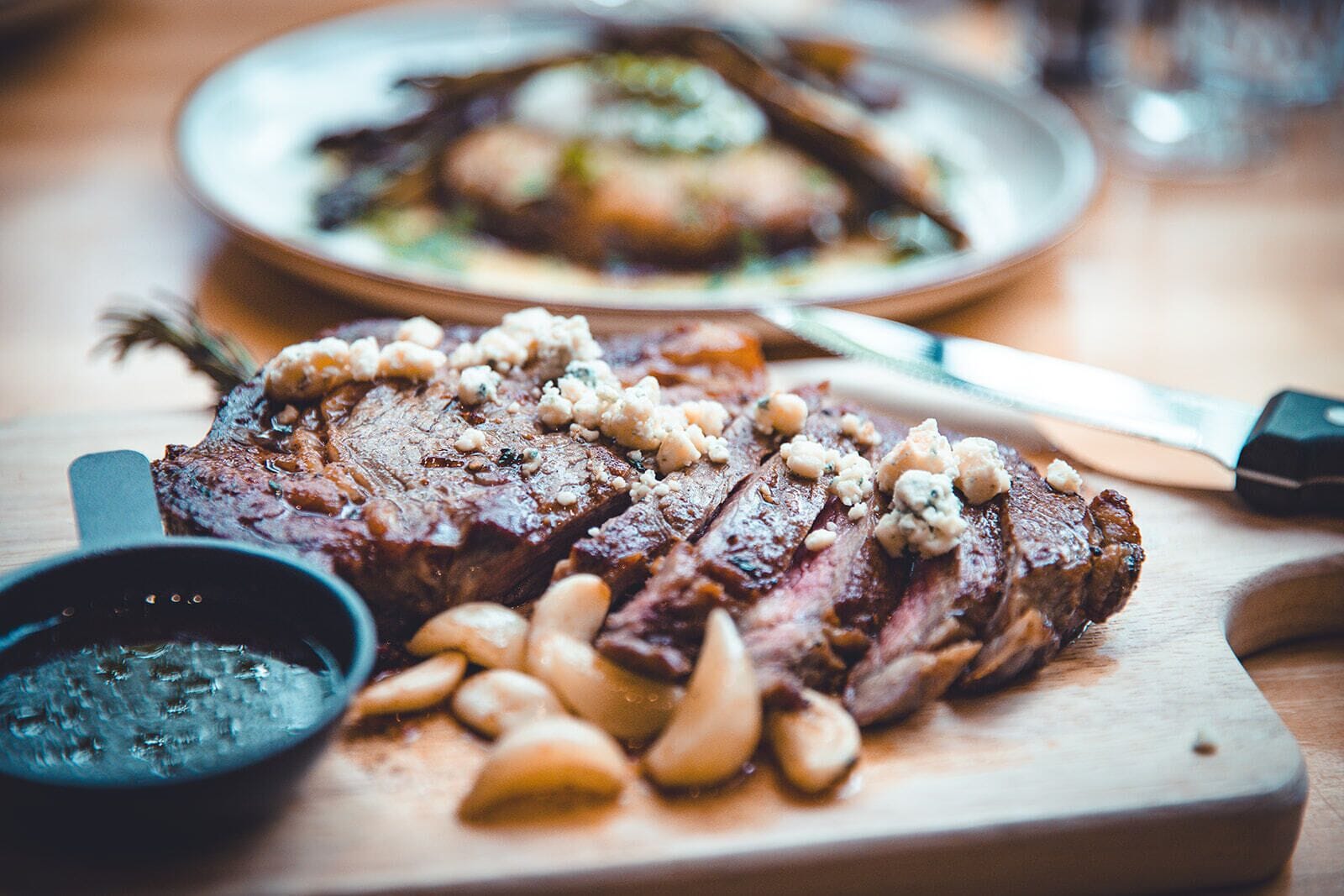 A steak with mushrooms and nuts on a wooden board.