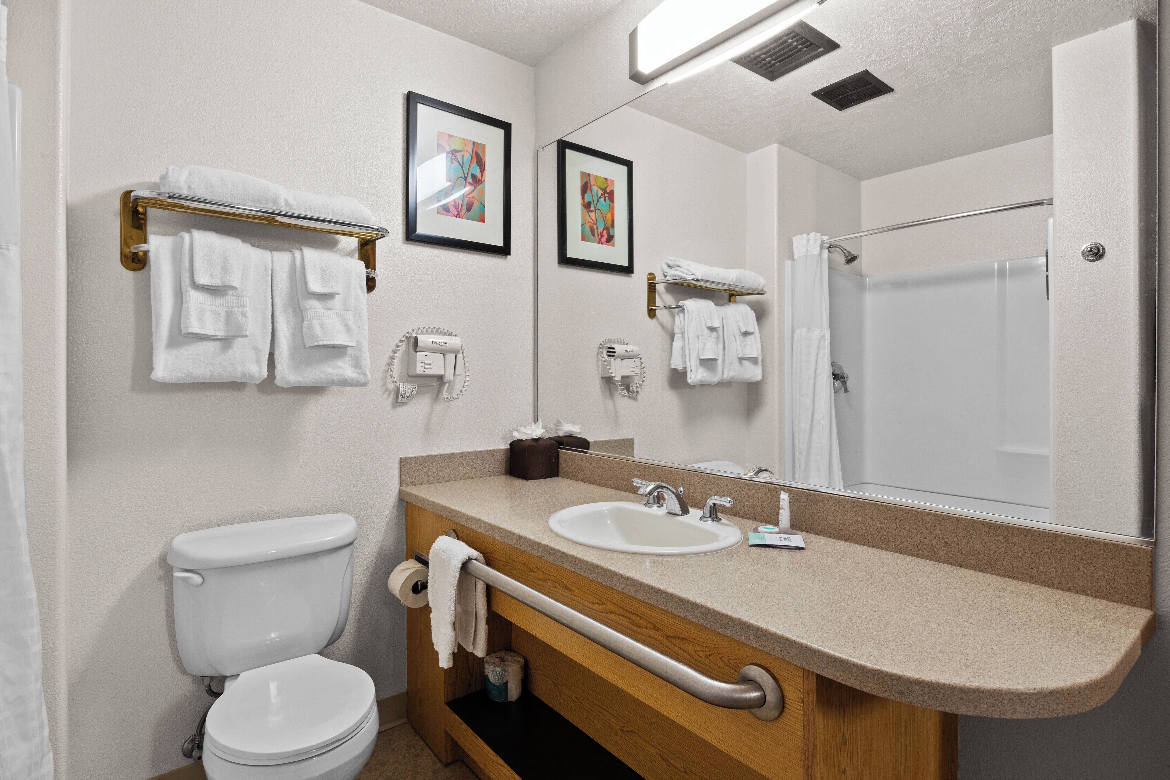 A bathroom with a toilet, sink, and shower. There are towels on the wall and a towel rack.