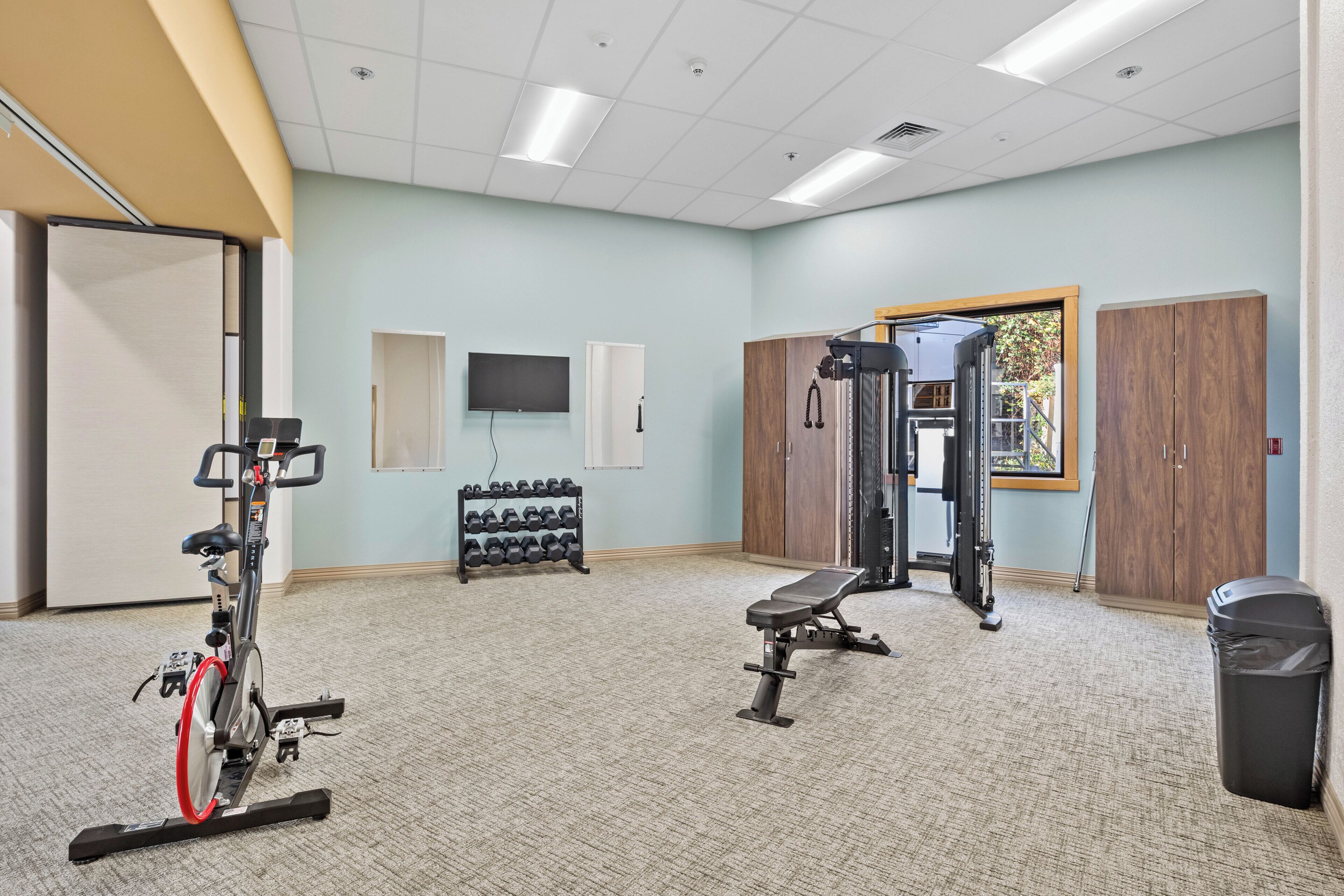 Un gimnasio con equipo de ejercicio, una televisión y una ventana con vistas.