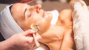 A person receiving a facial treatment with a brush.