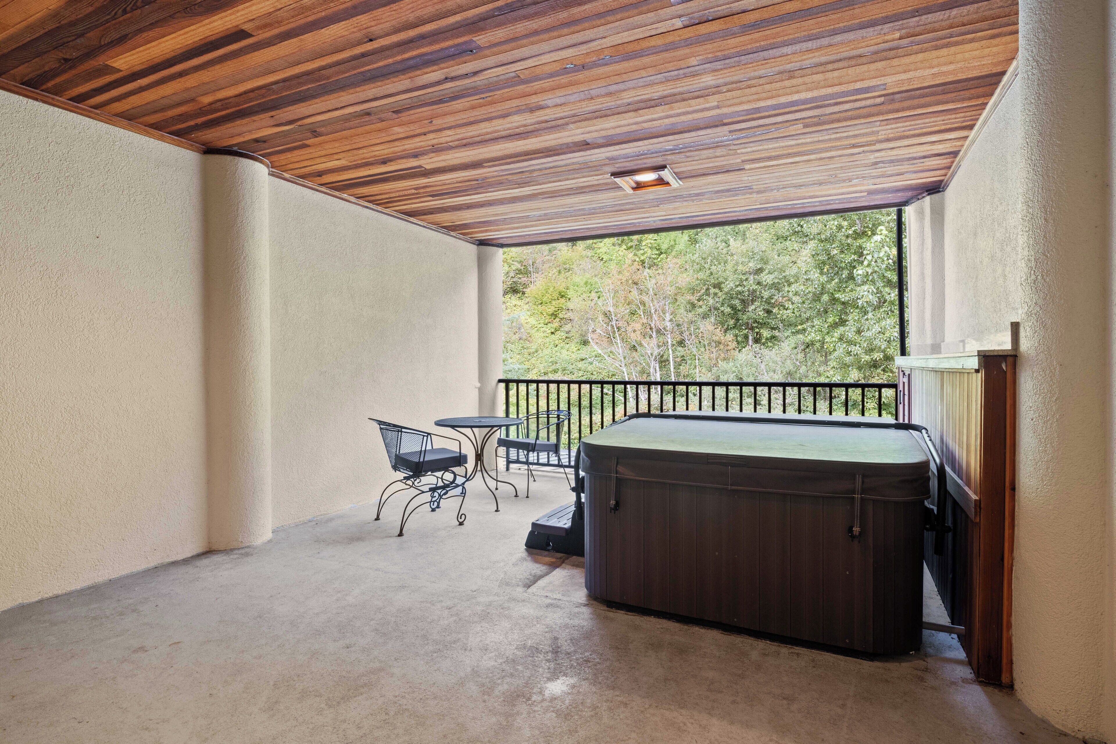 Un patio cubierto con un jacuzzi, una mesa y sillas.