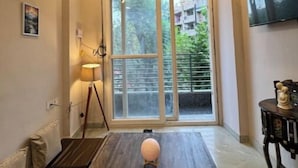 Une pièce avec un ventilateur de plafond, une table en bois, une lampe et un téléviseur fixé au mur.