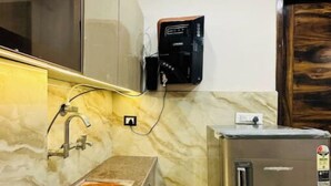 Une cuisine compacte dotée d’un plan de travail en marbre, d’un évier encastré et d’un réfrigérateur en acier inoxydable.