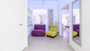 A room with a purple and yellow chair, white walls, and a large mirror. - Apartments Florence-San Lorenzo Market (Florence)