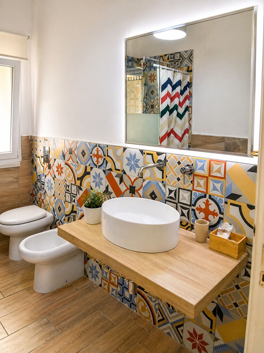 Un baño con dos inodoros, un lavabo con espejo y salpicadero de azulejos.
