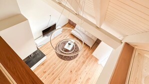 A modern loft-style room with a wooden floor, a circular light fixture, and a sofa. - VK - Zürich Airport - Luxury - Homestay  (Kloten)