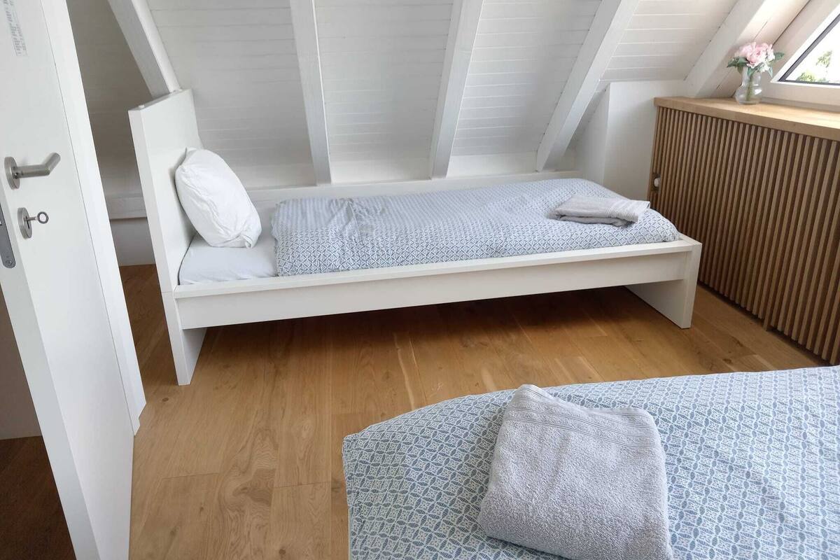 Un dormitorio pequeño estilo loft, con cama individual, piso de madera y ventana con vistas.