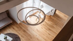 A modern interior with a circular light fixture, wooden flooring, and white furniture. - VK - Zürich Airport - Luxury - Homestay  (Kloten)