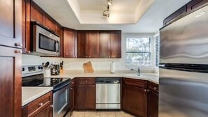 Una cocina con armarios de madera, electrodomésticos de acero inoxidable y una ventana que proporciona luz natural.