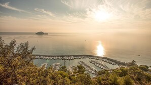 A marina with boats docked, a small island in the distance, and a clear sky. - 1 bedroom amazing home in Onzo (Onzo)