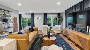 A modern living room with a sofa, two armchairs, a coffee table, and a TV. - 5 mi. to Asheville•HotTub•Sauna•MtnViews•FirePit•PoolTable (Swannanoa)