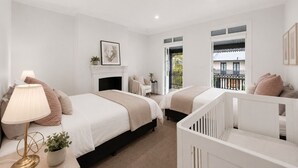 A bedroom with two beds, a fireplace, a balcony with a view, and a crib. - Darlinghurst Living | 5 Beds + Garage Parking (Darlinghurst)