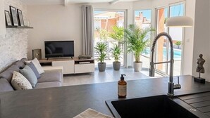 A modern living room with a flat-screen TV, sofa, and potted plants.