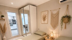 A modern bedroom with a bed, bedside table, and a hanging macrame plant.