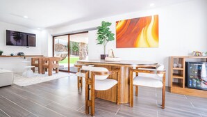 Un comedor moderno con una mesa y sillas de madera, un cuadro abstracto de gran tamaño y una planta en maceta.