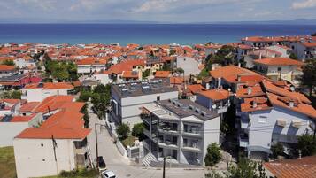 Un quartier résidentiel situé sur la côte, caractérisé par des toits recouverts de tuiles rouges, des bâtiments modernes et une vue sur la mer.