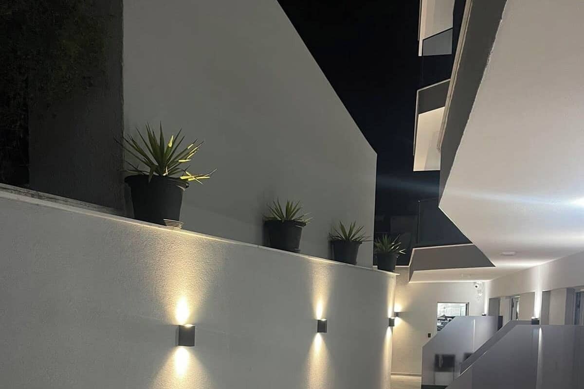 A modern interior with a long, narrow hallway, recessed lighting, and potted plants.