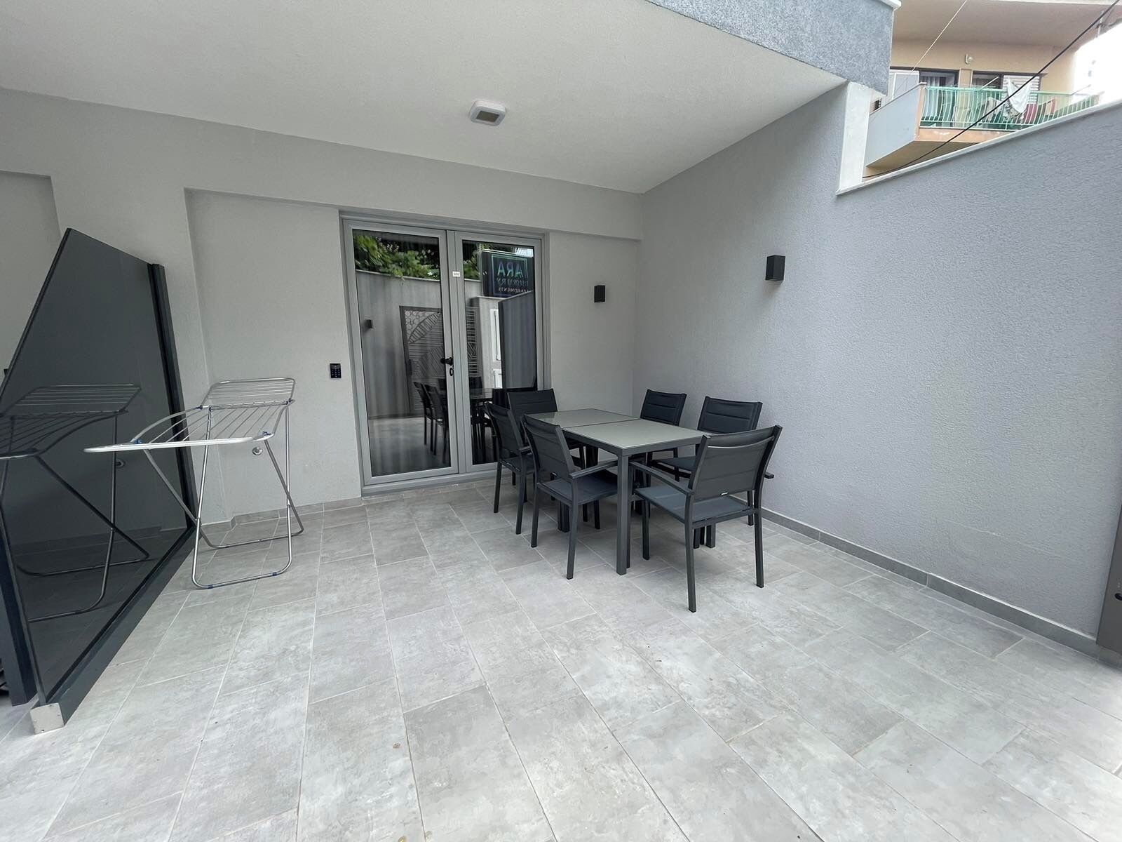 Un espace patio avec une table et des chaises, une porte-fenêtre coulissante et un étendoir à linge.