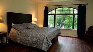 A bedroom with a large bed, a window with curtains, a nightstand with a lamp, and a chair. - Lakefront Hideaway - Boat Slip at Nearby Marina (Grove)