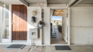 A wooden exterior with a metal door, a wall-mounted electrical box, and a covered outdoor area with a bench. - Stunning home in Blokhus with sauna (Blokhus)